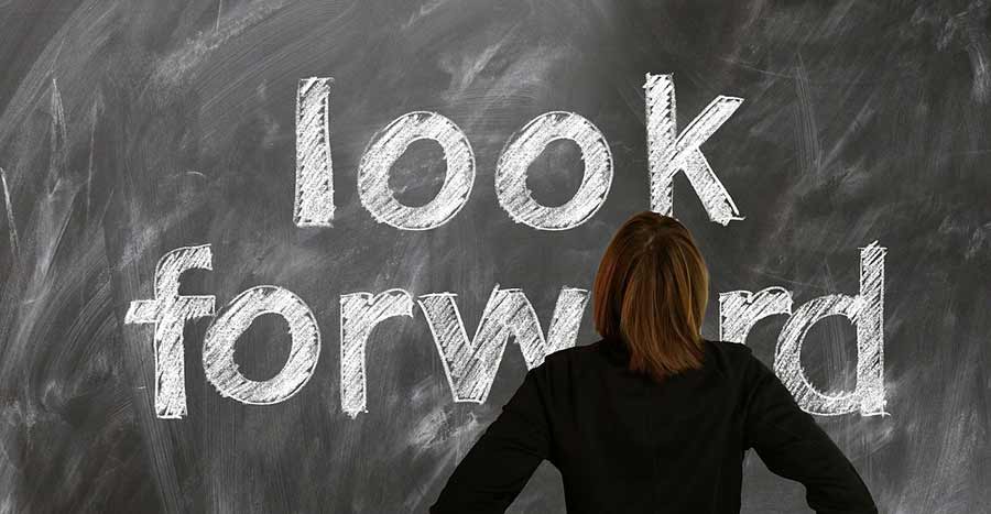 A woman is looking at a blackboard with Look Forward written on it.